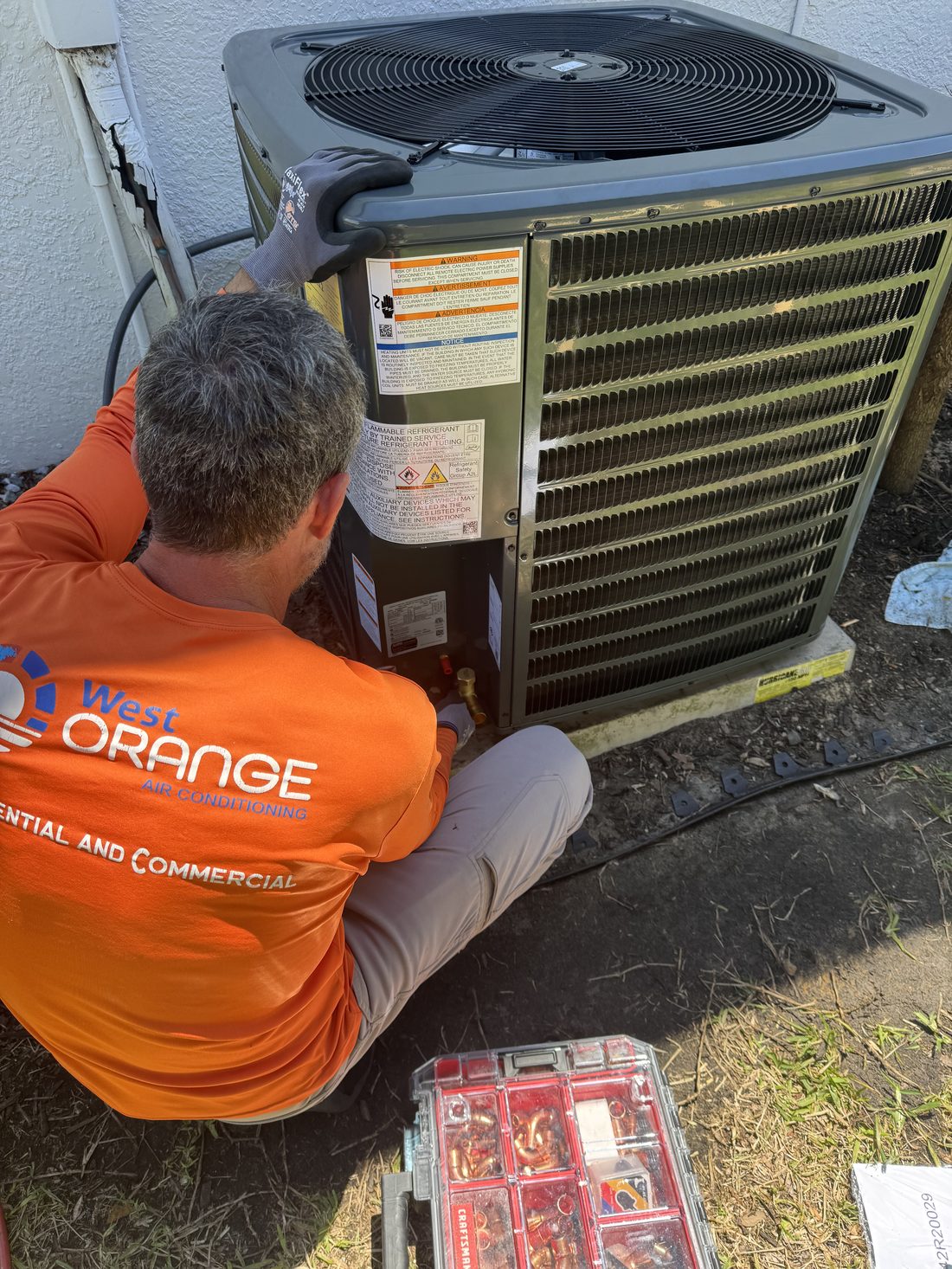 Technician testing an AC capacitor with a clamp meter during an emergency repair in Orlando