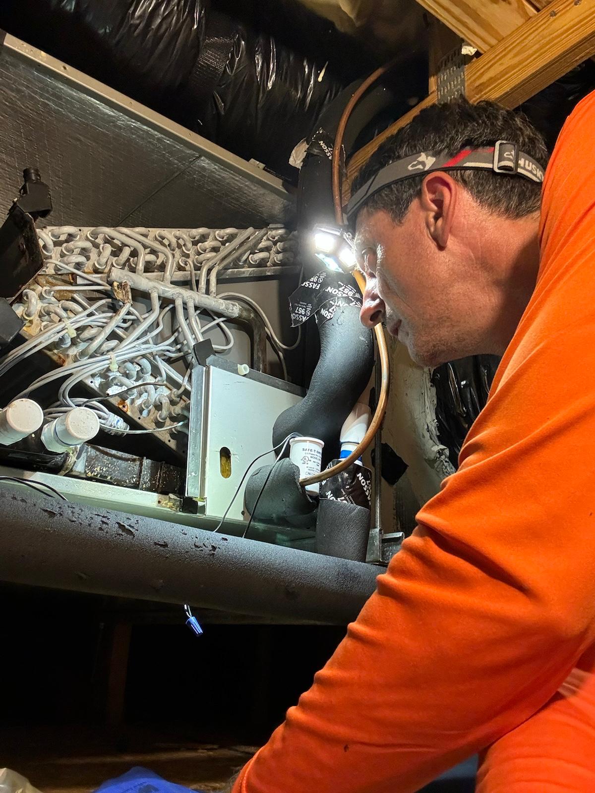 West Orange AC technician performing electrical diagnostics on an outdoor condensing unit