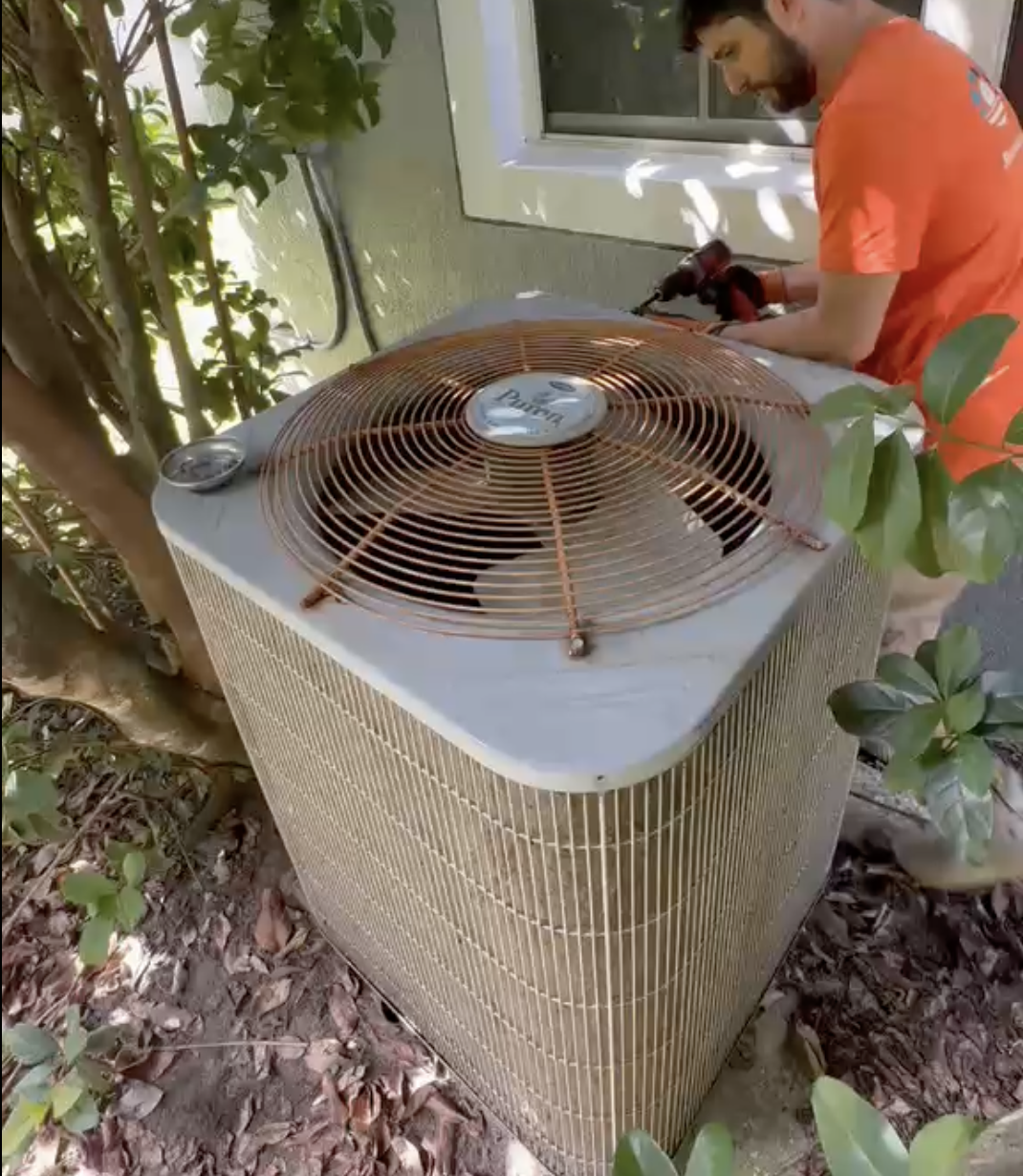 Technician cleaning a badly clogged condenser coil on a commercial rooftop unit in Orlando